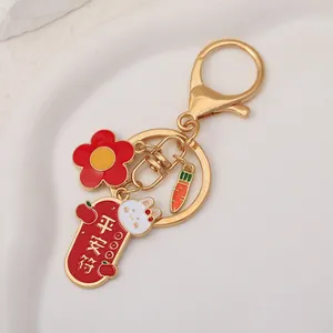 Detailed close-up of a golden rabbit keychain with red flower and safety charm pendants
