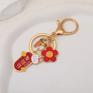 Detail of golden Chinese rabbit keychain with red luck charm, flower and carrot charms