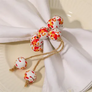 Close-up of wooden bead napkin ring with autumn maple leaf pattern and jute tassels