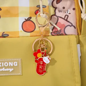 Close-up of golden rabbit safety charm keychain on yellow checkered pattern bag