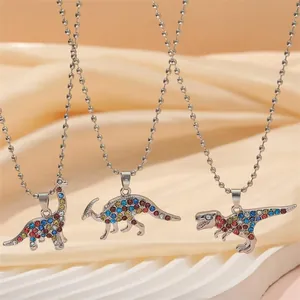 Three colorful dinosaur BFF necklaces with sparkling rhinestones on a silk background