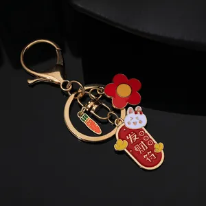 Detailed close-up of a golden metal rabbit keychain with fortune banner and flower charms