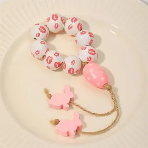 Portatovaglioli con perline di legno rosa e coniglietti su un piatto di ceramica