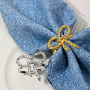 Detalle de servilletero de lazo dorado con textura de cuerda sobre servilleta azul