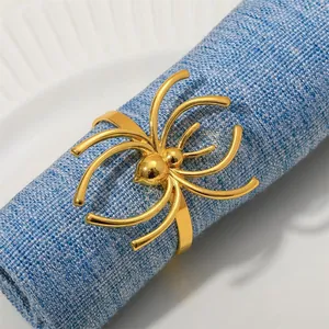 Détail d'un rond de serviette en forme d'araignée dorée sur une serviette en lin bleu