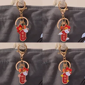 Detail of metal rabbit keychains with Chinese lucky charms on a grey canvas bag