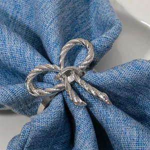 Detalle del servilletero de lazo plateado con textura de cuerda sobre tela azul