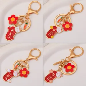 Four Chinese style rabbit keychains with lucky charms and flowers on a stone surface