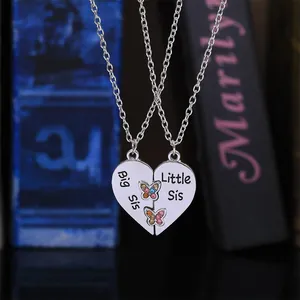Vue détaillée du collier coeur Big Sis et Little Sis en argent avec des papillons