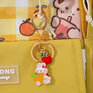 Detail of cute bunny keychain with apple charm on a yellow plaid bag showing gold hardware
