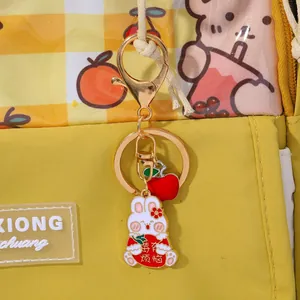 Detail shot of cute bunny plush keychain with red lucky bag on yellow backpack