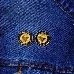 Detailopname van Employee of the Month en Excellence in Service emaille pins op denim