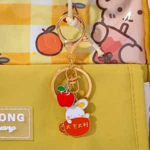Detail of bunny and red apple charm keychain on yellow checkered bag for luck