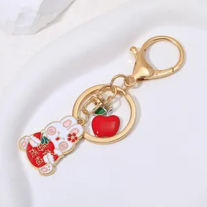 Cute bunny keychain with apple charm, gold metal hardware on elegant ceramic tray
