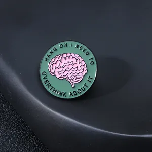 Dettaglio spilla in smalto verde con cervello rosa e testo motivazionale sulla salute