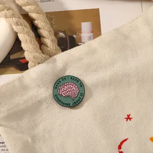 Dettaglio di una spilla rotonda a forma di cervello su una borsa di tela bianca