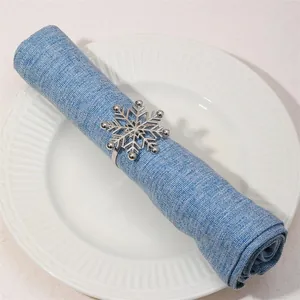 Detail view of silver snowflake napkin ring on blue linen napkin and white ceramic plate