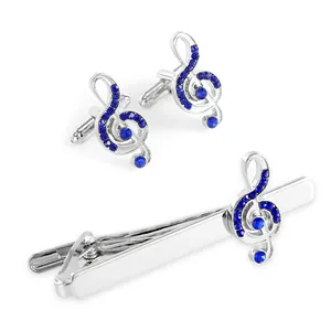 Detailed view of silver treble clef cufflinks and tie clip set with blue crystals