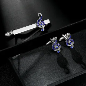 Macro detail of music note tie clip and cufflinks set with blue crystal inlay