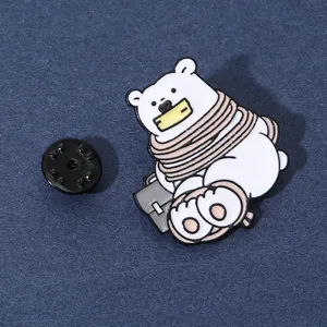 Macro dettaglio di una spilla smaltata con orso polare e borsa su sfondo blu scuro
