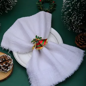 Detail shot of Christmas napkin ring with double bells on white fabric and green table