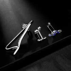 Macro detail of silver music note tie clip and cufflinks set with blue rhinestones