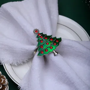 Close-up of a silver Christmas tree napkin ring with green enamel and red crystals on linen