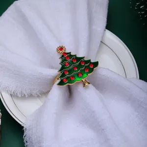 Close-up of a golden Christmas tree napkin ring with green enamel and red rhinestones