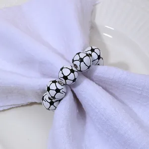 Vue détaillée du rond de serviette football avec perles noires et blanches sur table
