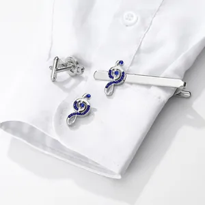 Detail of silver musical note cufflinks and tie clip with blue crystals on shirt cuff