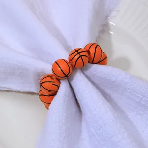 Détail du rond de serviette basket avec perles en bois orange sur serviette en tissu blanc