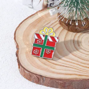 Christmas gift box enamel brooch with red ribbon and silver snowflake on wood base
