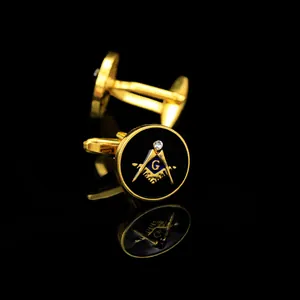Macro detail of gold Freemasonry cufflinks with black enamel inlay and crystal on black mirror