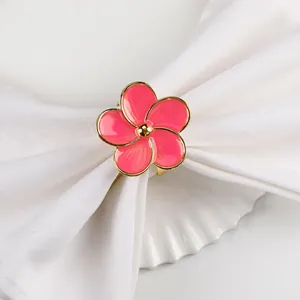 Dettaglio portatovagliolo a fiore rosa con placcatura in oro e elegante panno bianco