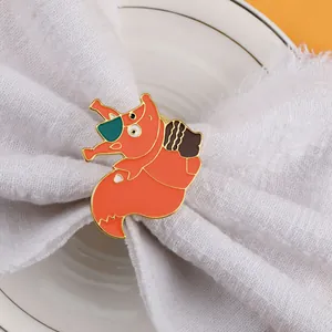 Detail view of squirrel napkin ring in orange enamel with gold finish on white linen