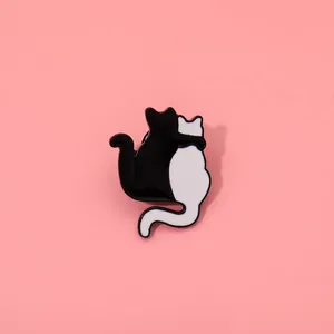 Detailed close-up of a cute black and white enamel cat badge with floral accents