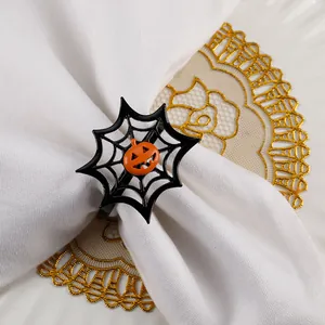 Close-up of black spider web napkin ring with pumpkin detail on white linen