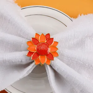 Detail of red and orange sunflower napkin ring on a white cloth with golden edges