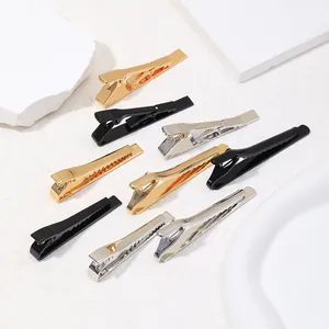 Barrettes bec de canard en métal poli en or, argent et noir sur fond de marbre blanc