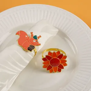 Detail of enamel squirrel and sunflower napkin rings on white ceramic plate