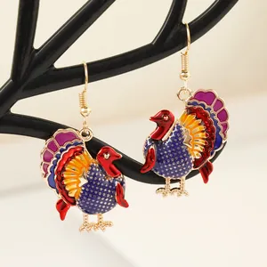 Detailed macro of festive turkey earrings with colorful enamel and gold-tone finish