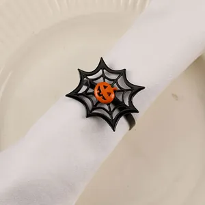 Detail of black spider web napkin ring with a Jack-o'-lantern on a white fabric napkin