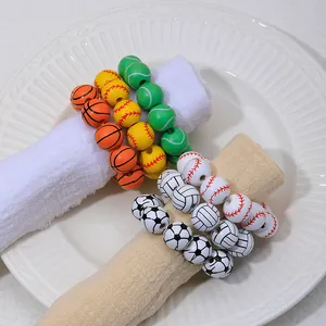 Lot de ronds de serviette thème sport avec perles de basket et foot sur serviette blanche