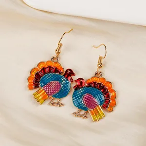 Detail of colorful enamel turkey earrings with gold alloy frame on silk background