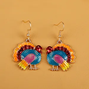 Macro shot of colorful turkey enamel drop earrings with gold alloy hooks for Thanksgiving