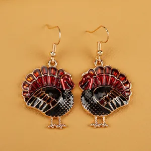 Detail of turkey earrings with red enamel feathers and golden metallic frames