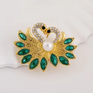 Elegant gold-plated double swan brooch with green marquise crystals and a white pearl