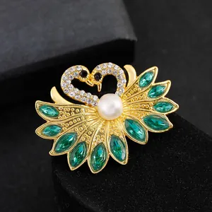 Detailed view of swan brooch with green marquise crystals and a central pearl