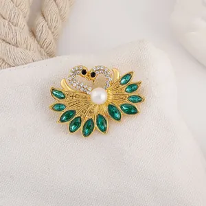 Detailed close-up of a golden double swan brooch with crystal inlay and white pearl on canvas