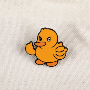 Gros plan d'un pin's canard jaune en émail faisant un geste du doigt sur toile